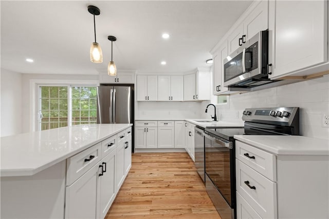 kitchen with stainless steel appliances, a sink, white cabinetry, light wood-style floors, and light countertops