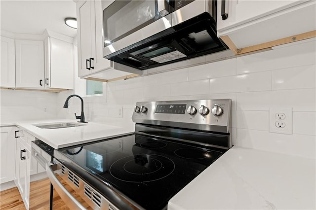 kitchen featuring a sink, white cabinetry, light countertops, appliances with stainless steel finishes, and tasteful backsplash