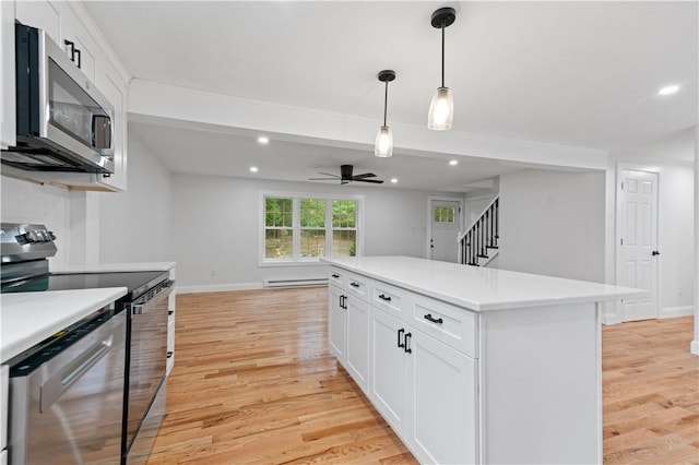 kitchen with light wood-type flooring, white cabinetry, appliances with stainless steel finishes, and light countertops