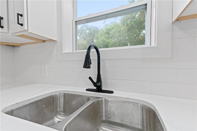 details with backsplash, white cabinets, a sink, and light countertops