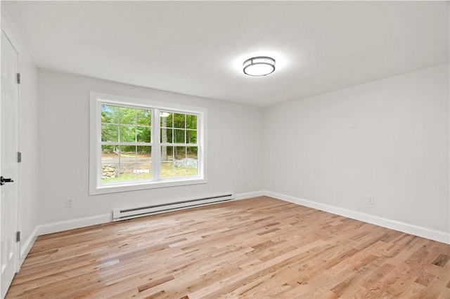 spare room with a baseboard heating unit, light wood-style floors, and baseboards