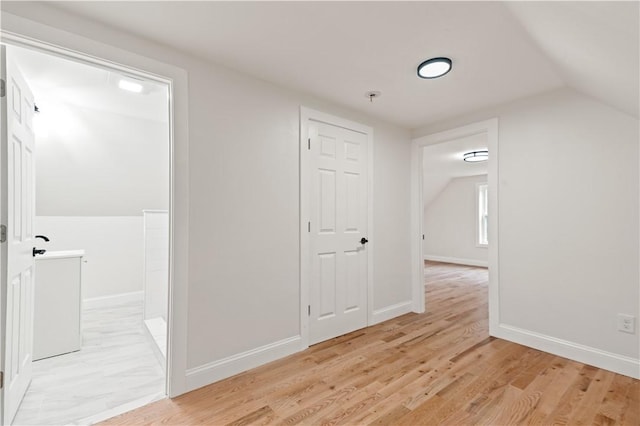 interior space featuring light wood-type flooring, baseboards, and lofted ceiling