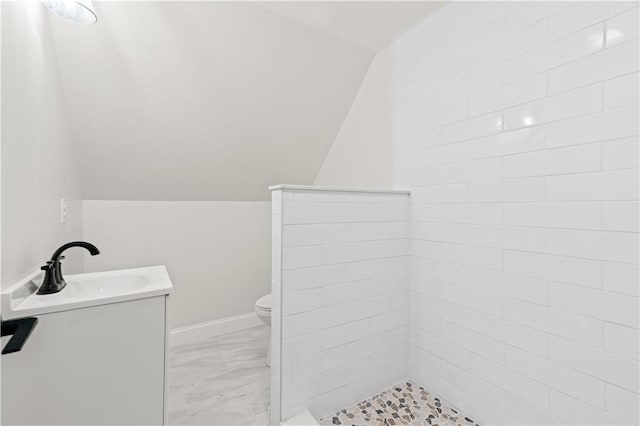 bathroom with vaulted ceiling, marble finish floor, vanity, and toilet