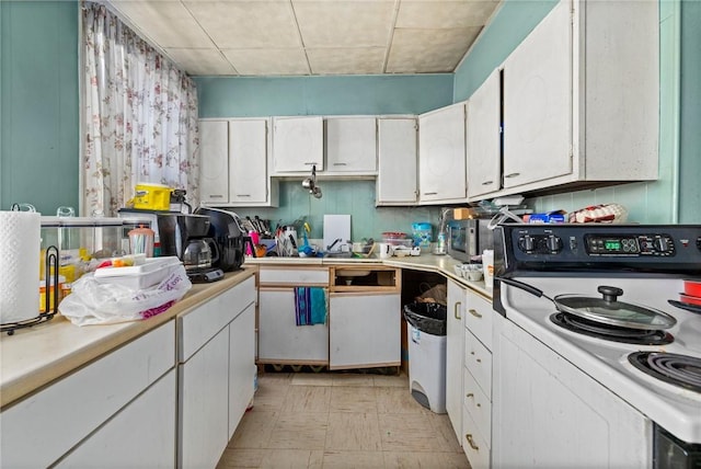 kitchen featuring light floors, electric range, white cabinets, and light countertops