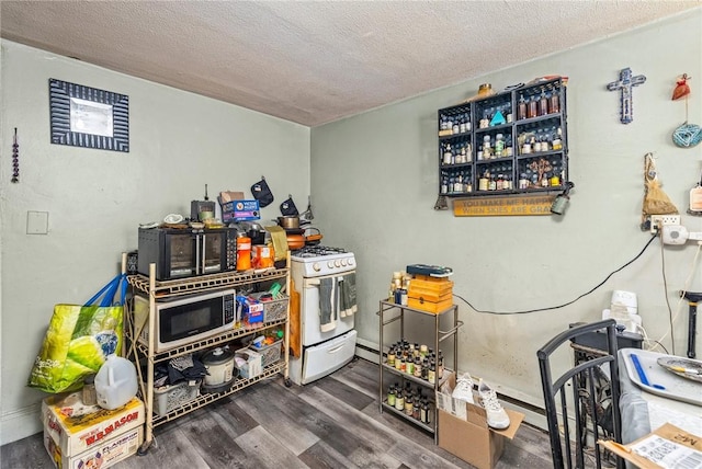 kitchen with a textured ceiling, white range with gas stovetop, black microwave, and wood finished floors