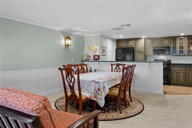 dining room featuring a wainscoted wall, crown molding, visible vents, and light colored carpet