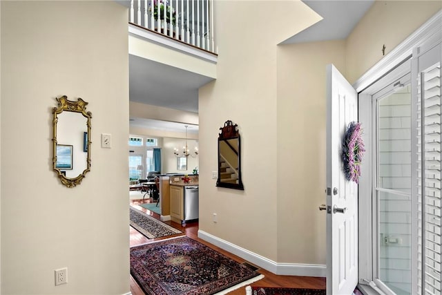 foyer entrance with a chandelier, dark wood finished floors, and baseboards
