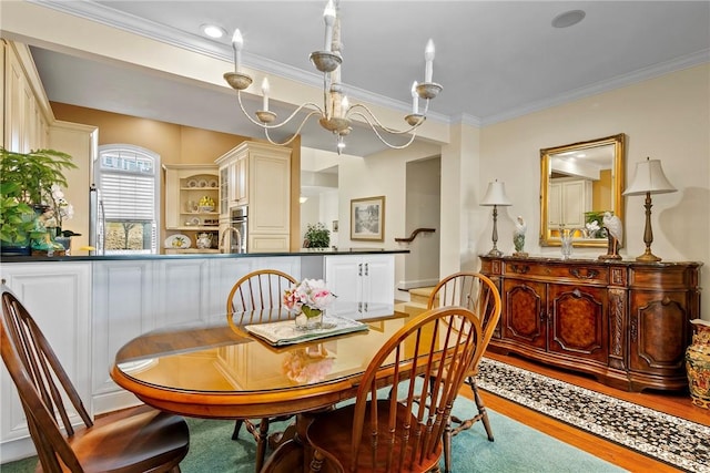 dining room with light wood finished floors, crown molding, and a notable chandelier