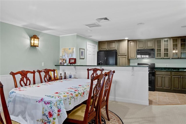 dining area with light carpet, crown molding, visible vents, and light tile patterned floors
