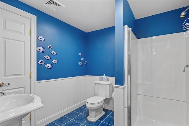 full bathroom featuring a stall shower, visible vents, wainscoting, tile patterned flooring, and a sink