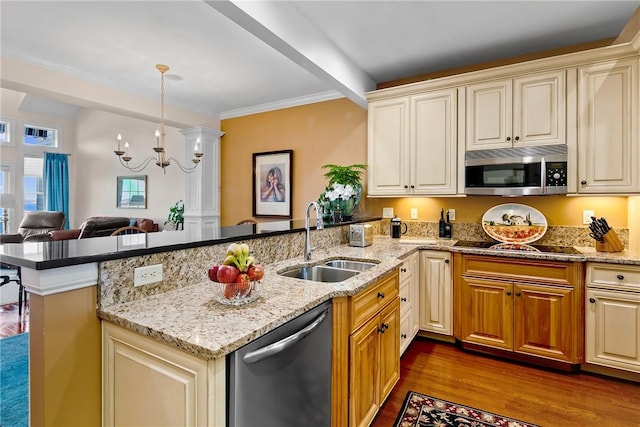 kitchen featuring a peninsula, cream cabinetry, stainless steel appliances, and a sink