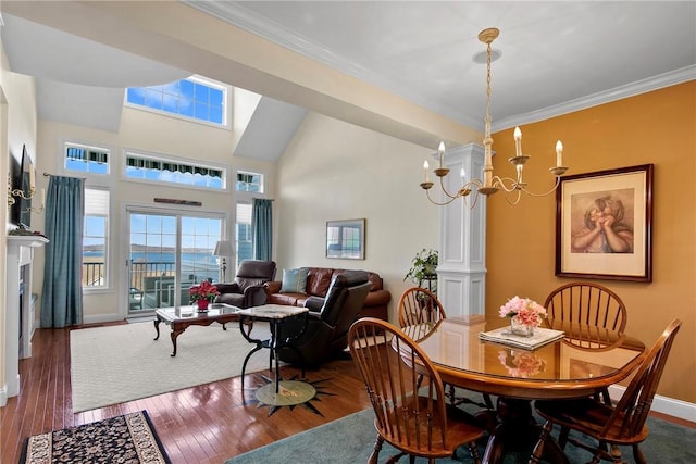 dining area with a towering ceiling, baseboards, ornamental molding, wood-type flooring, and an inviting chandelier