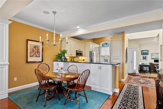dining space featuring ornamental molding, baseboards, a notable chandelier, and light wood finished floors