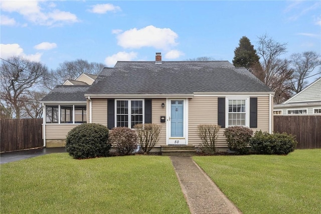 view of front of house with a chimney, roof with shingles, a front lawn, and fence