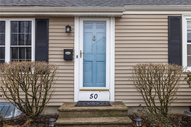 doorway to property with roof with shingles