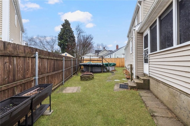 view of yard with a fire pit, a fenced backyard, and entry steps