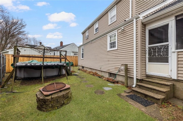 view of yard featuring a fenced in pool, entry steps, a fire pit, and fence