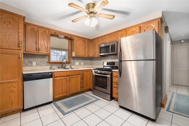 kitchen featuring a sink, tasteful backsplash, appliances with stainless steel finishes, brown cabinetry, and light countertops