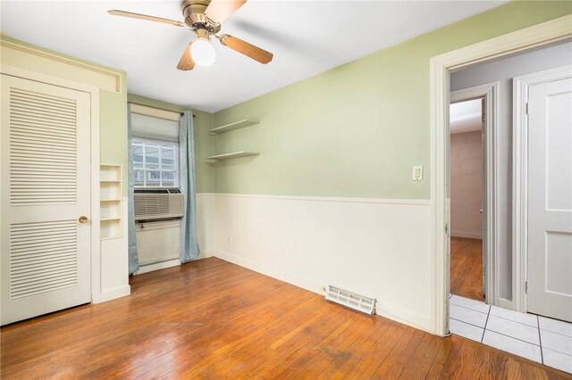 unfurnished bedroom with visible vents, cooling unit, ceiling fan, and wood finished floors