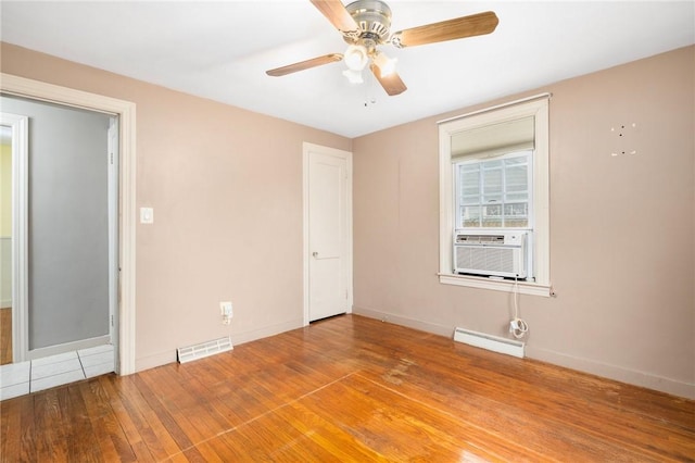 unfurnished room featuring visible vents, cooling unit, wood-type flooring, a baseboard radiator, and baseboards