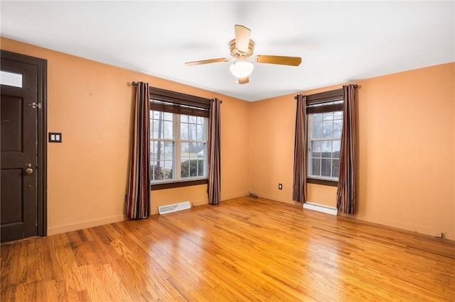 spare room featuring light wood-type flooring, visible vents, baseboards, and ceiling fan