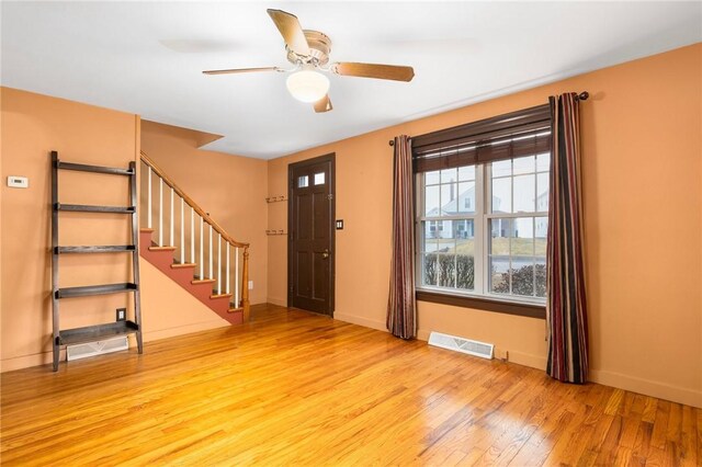 foyer with stairway, a ceiling fan, visible vents, baseboards, and light wood-style flooring