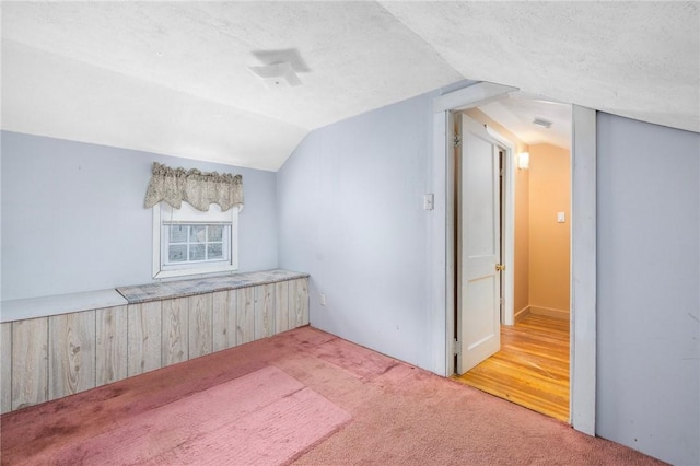 carpeted spare room featuring a textured ceiling and vaulted ceiling