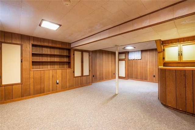 finished basement with wooden walls, baseboards, carpet, and built in features