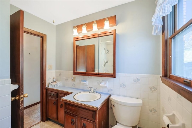 full bath with a wainscoted wall, tile walls, toilet, vanity, and walk in shower