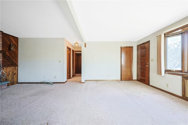 unfurnished living room featuring baseboards, beamed ceiling, and light colored carpet