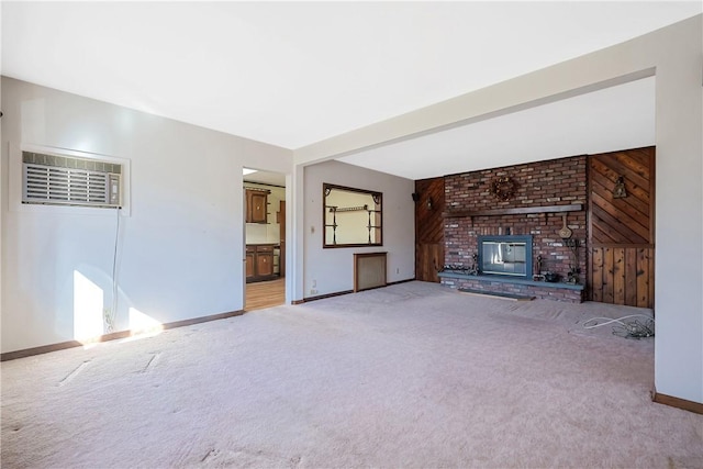 unfurnished living room with carpet floors, a fireplace, wood walls, a wall mounted air conditioner, and baseboards