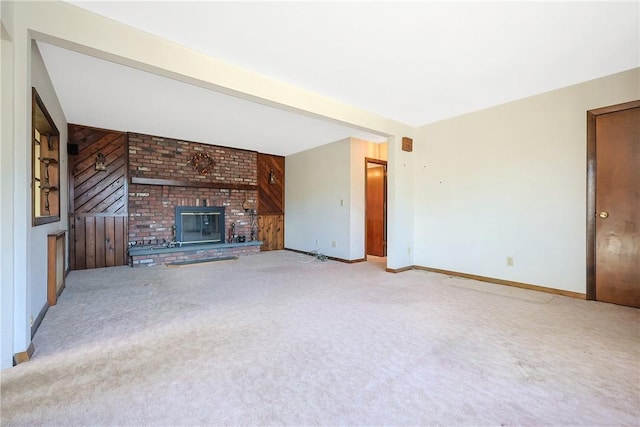 unfurnished living room with wood walls, carpet, a fireplace, and baseboards