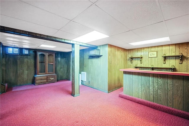 bar with a paneled ceiling, wooden walls, carpet, and wet bar