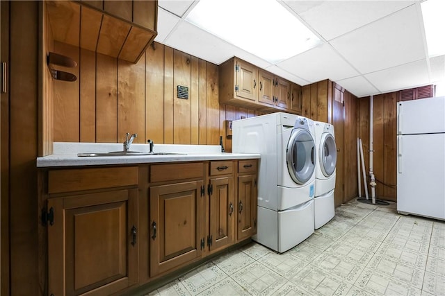 clothes washing area featuring washing machine and dryer, cabinet space, a sink, and light floors