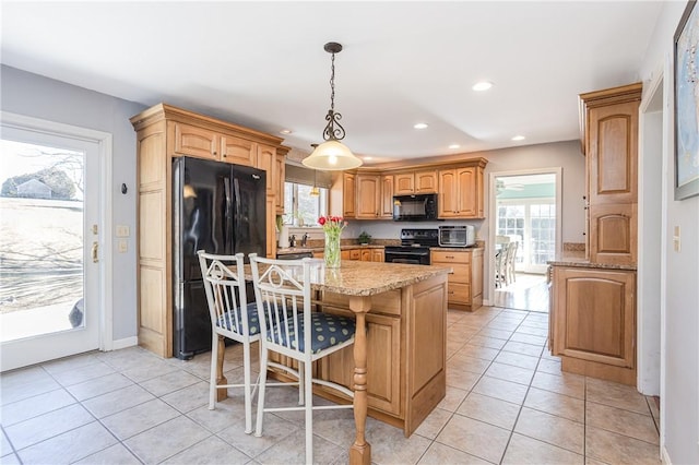 kitchen featuring light tile patterned floors, a center island, black appliances, pendant lighting, and recessed lighting