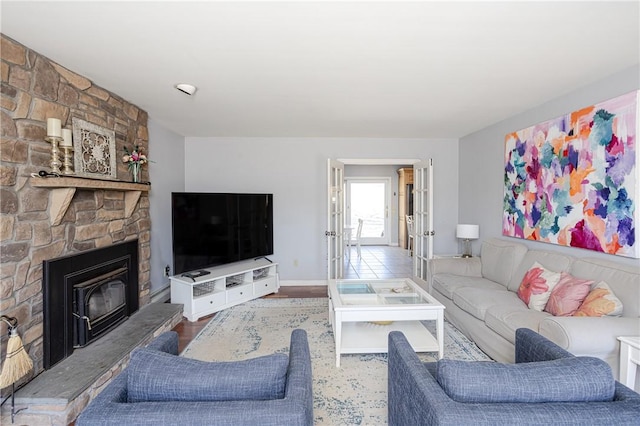 living room with a large fireplace, wood finished floors, and baseboards