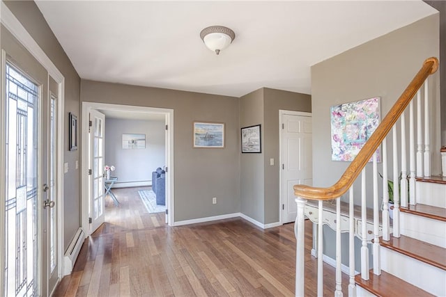 entryway with a baseboard heating unit, stairs, baseboards, and wood finished floors