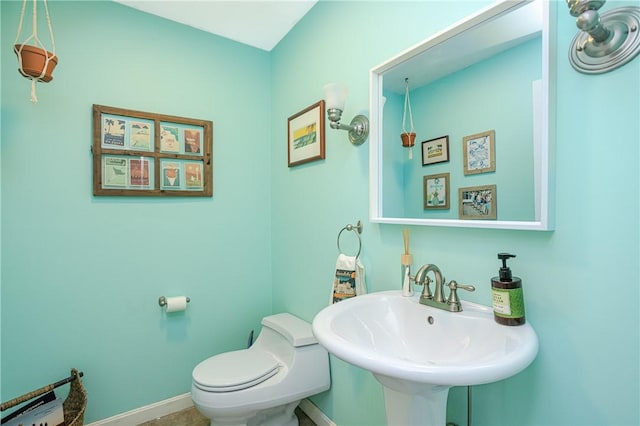 bathroom featuring a sink, toilet, and baseboards