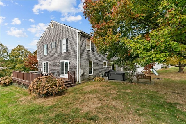 rear view of house featuring a playground, a lawn, a hot tub, and a wooden deck