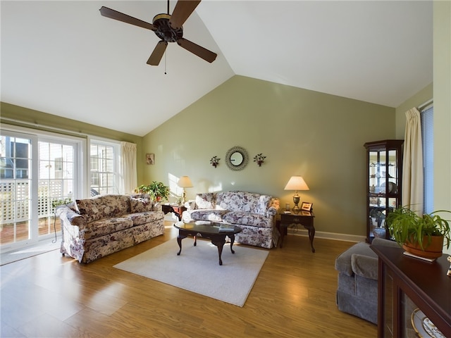 living area with lofted ceiling, ceiling fan, baseboards, and wood finished floors