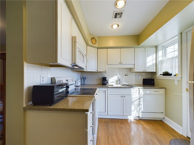 kitchen with light wood-type flooring, white appliances, white cabinets, and backsplash