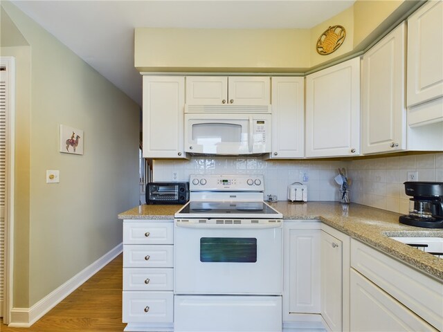 kitchen featuring white appliances, tasteful backsplash, baseboards, wood finished floors, and white cabinetry