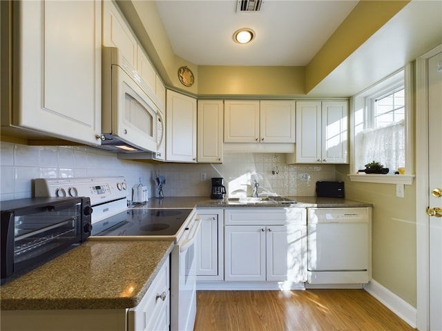 kitchen featuring white appliances, visible vents, backsplash, light wood-type flooring, and a sink