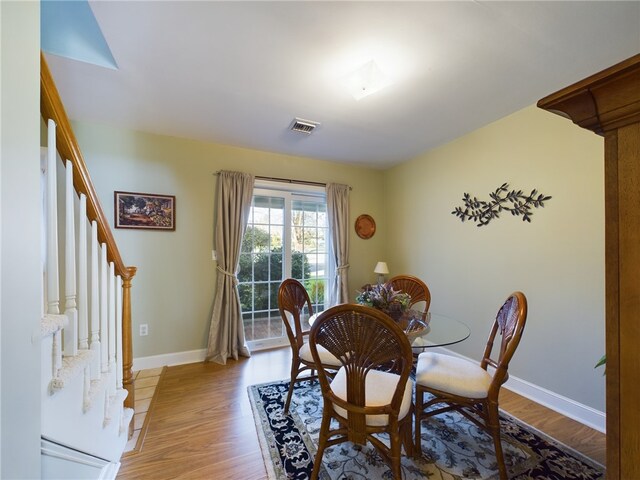 dining space featuring light wood-style flooring, stairway, and baseboards