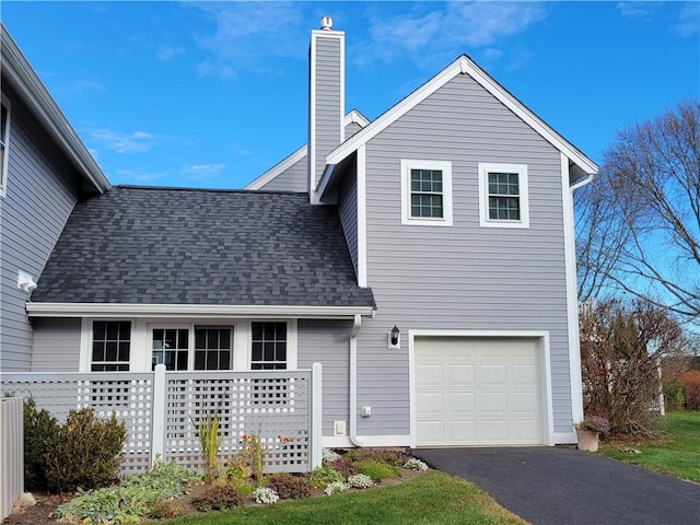 exterior space featuring roof with shingles, aphalt driveway, a chimney, and an attached garage