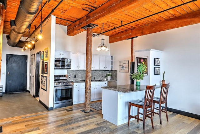 kitchen featuring wooden ceiling, beam ceiling, appliances with stainless steel finishes, and backsplash