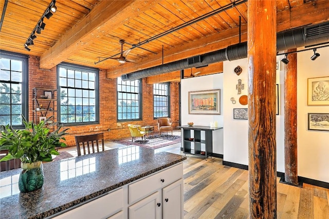 kitchen with beam ceiling, light wood finished floors, wood ceiling, white cabinetry, and brick wall