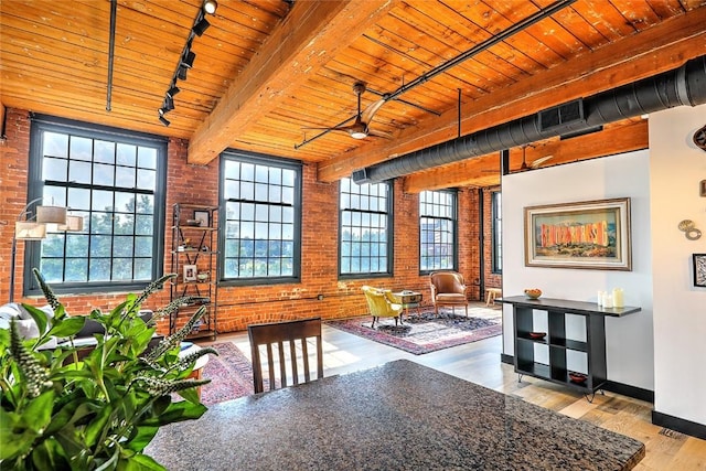 dining room with brick wall, wood finished floors, wood ceiling, beam ceiling, and rail lighting