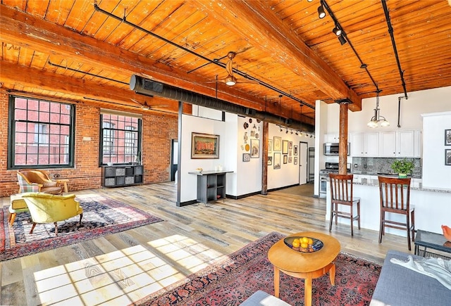 living room with wooden ceiling, brick wall, light wood-style floors, beam ceiling, and rail lighting