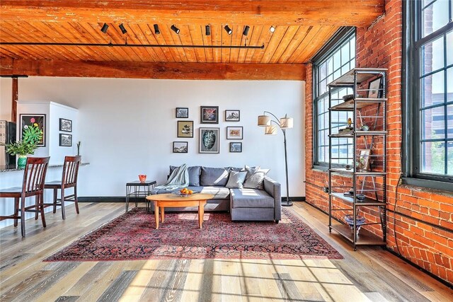 living area with brick wall, wooden ceiling, wood finished floors, and baseboards